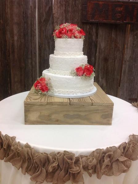 A 3 tier white wedding cake with fresh roses.