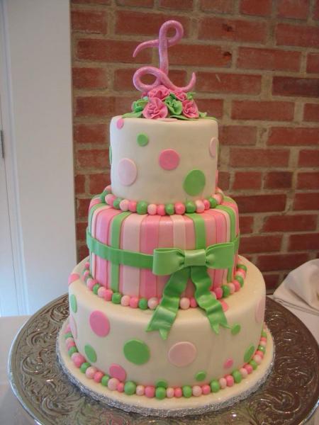 A pink and green wedding cake with polka dots and stripes.