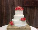 A 3 tier white wedding cake with fresh roses.