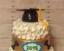 A 3 tiered graduation cake with various prints on each tier and a graduation cap as the cake topper.