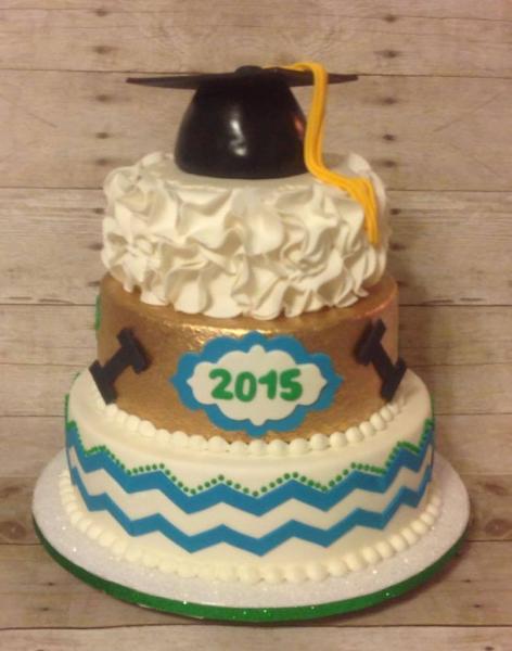 A 3 tiered graduation cake with various prints on each tier and a graduation cap as the cake topper.