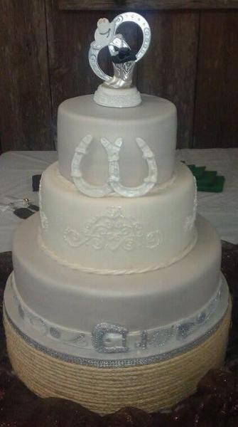 A unique wedding cake with a belt buckle and horseshoes.