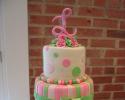 A pink and green wedding cake with polka dots and stripes.