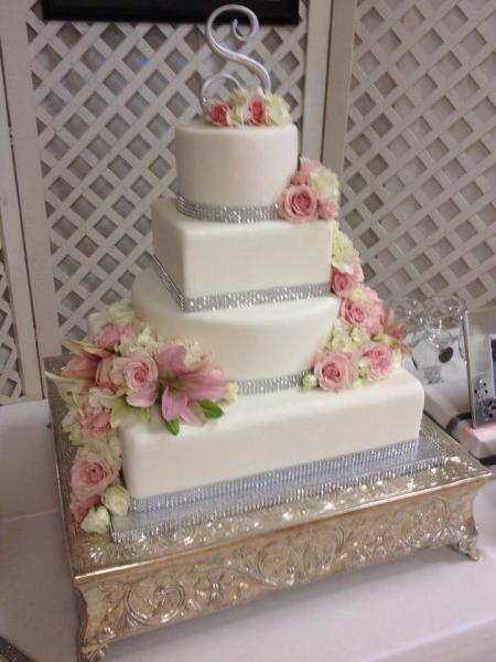 A 4 tier wedding cake with various shapes as well as crystal embellishment.