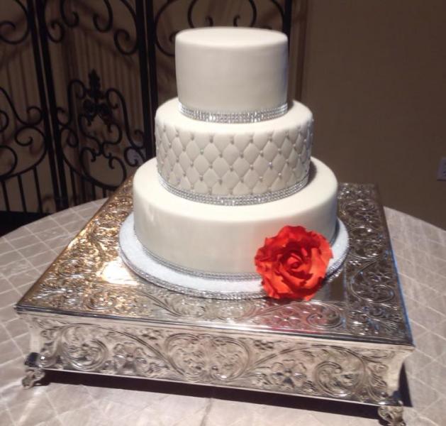 A beautiful wedding cake with an orange rose.