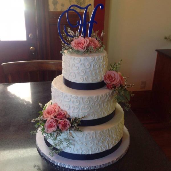 A beautiful 3 tiered wedding cake with beautiful designs and fresh flowers.